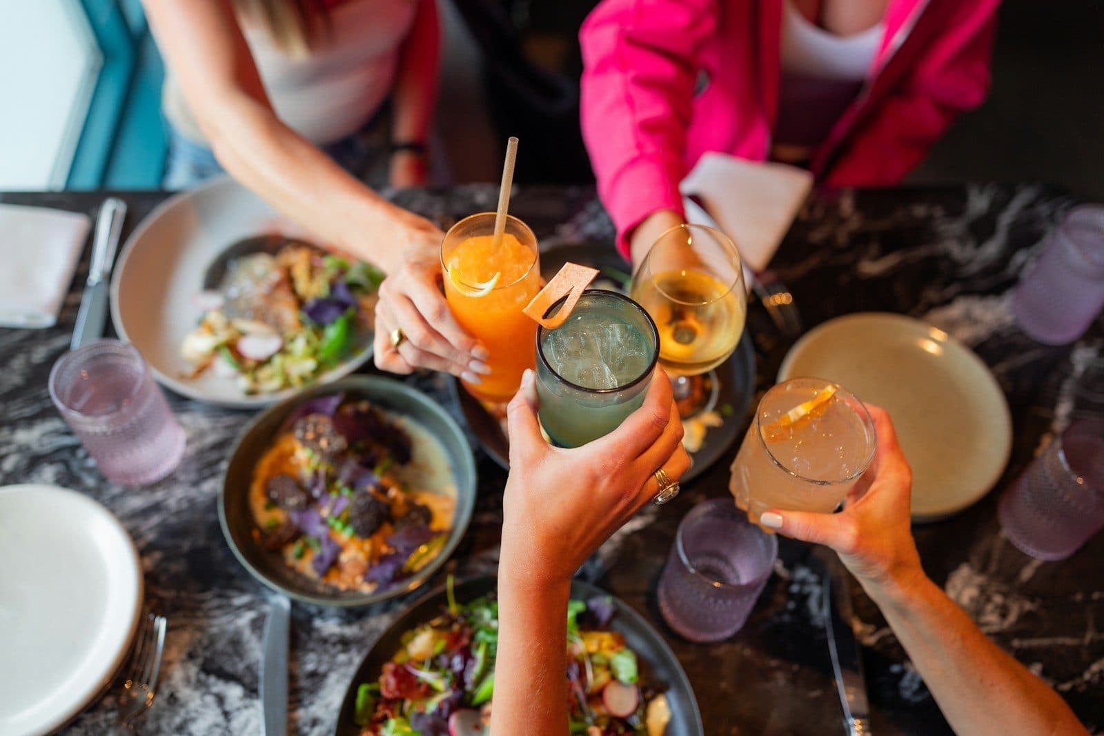 Friends raising cocktails in a toast over a dinner table